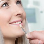 smiling female dental veneer patient evaluating options at consultation