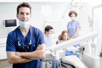 smiling cosmetic dentist with patient getting dental treatment