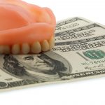 mold of upper teeth resting on a stack of $100 bills