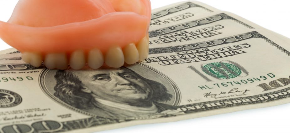 mold of upper teeth resting on a stack of $100 bills