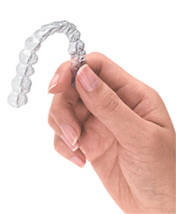 close up of a hand holding a clear dental aligner