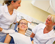 female dental patient smiling with dentist and dental assistant