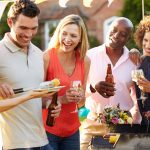 Friends drinking and smiling around barbecue